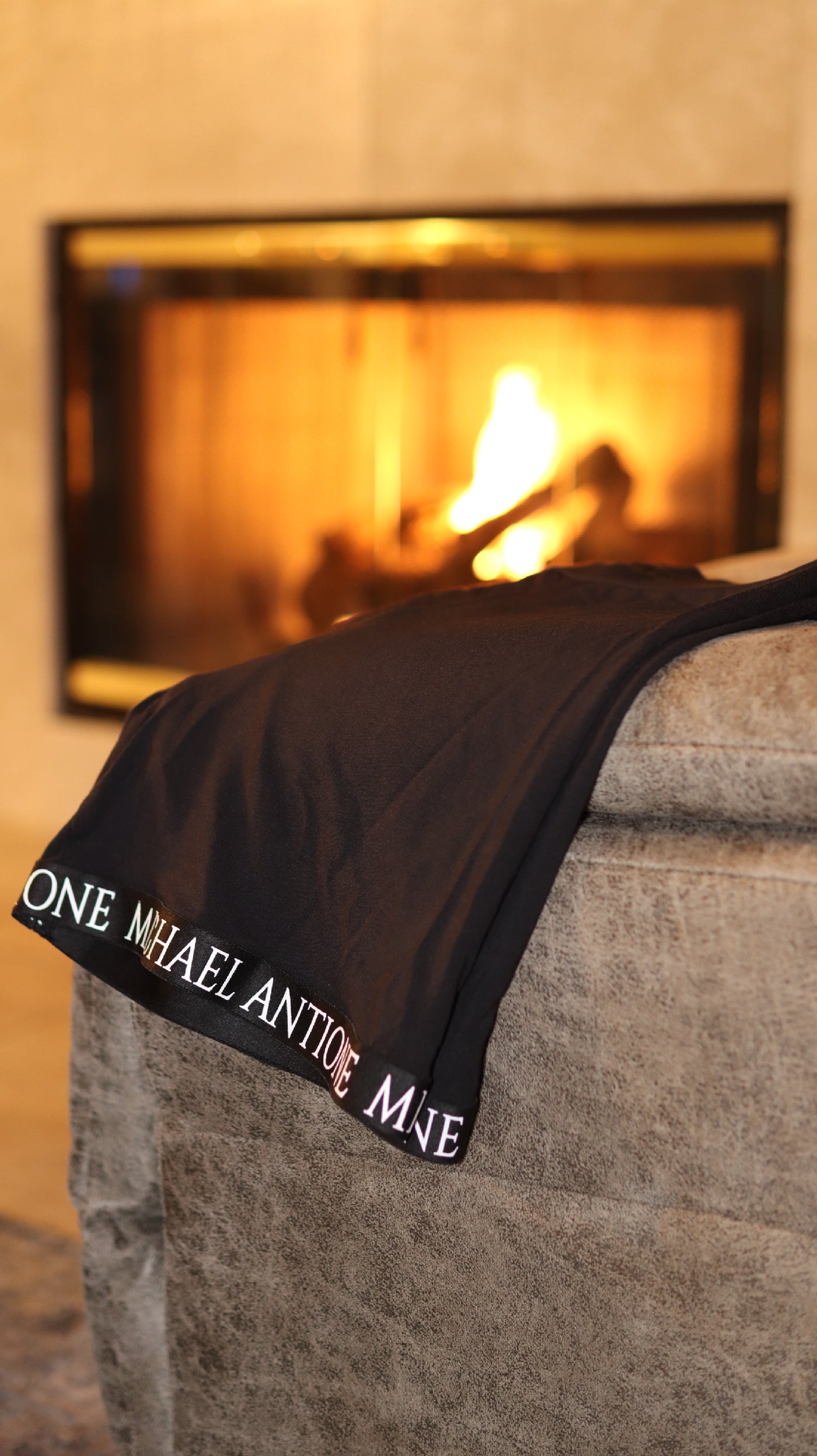 Black boxer briefs draped over the corner of a couch in front of a fireplace